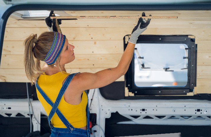 Frau nimmt Maße in einem ausgebauten Transporter.